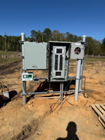 Outdoor service pedestal on rigid conduit risers, with a meter base, an open panelboard, a side enclosure, and an irrigation controller.